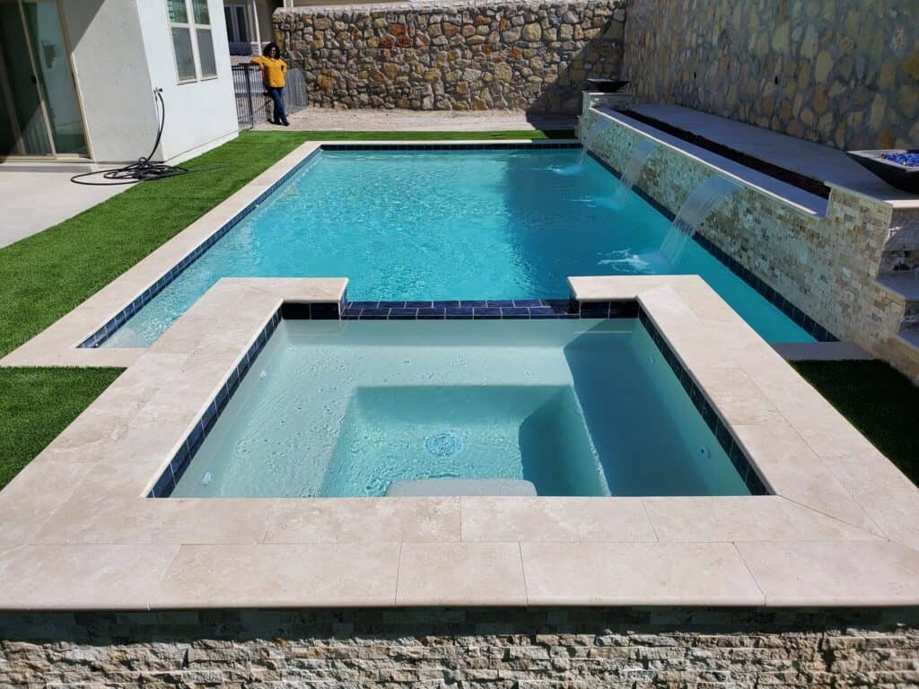 Front-facing view of a custom rectangular pool with an attached raised spa and clean stone coping, built by Eraland’s Custom Pools in El Paso, TX.